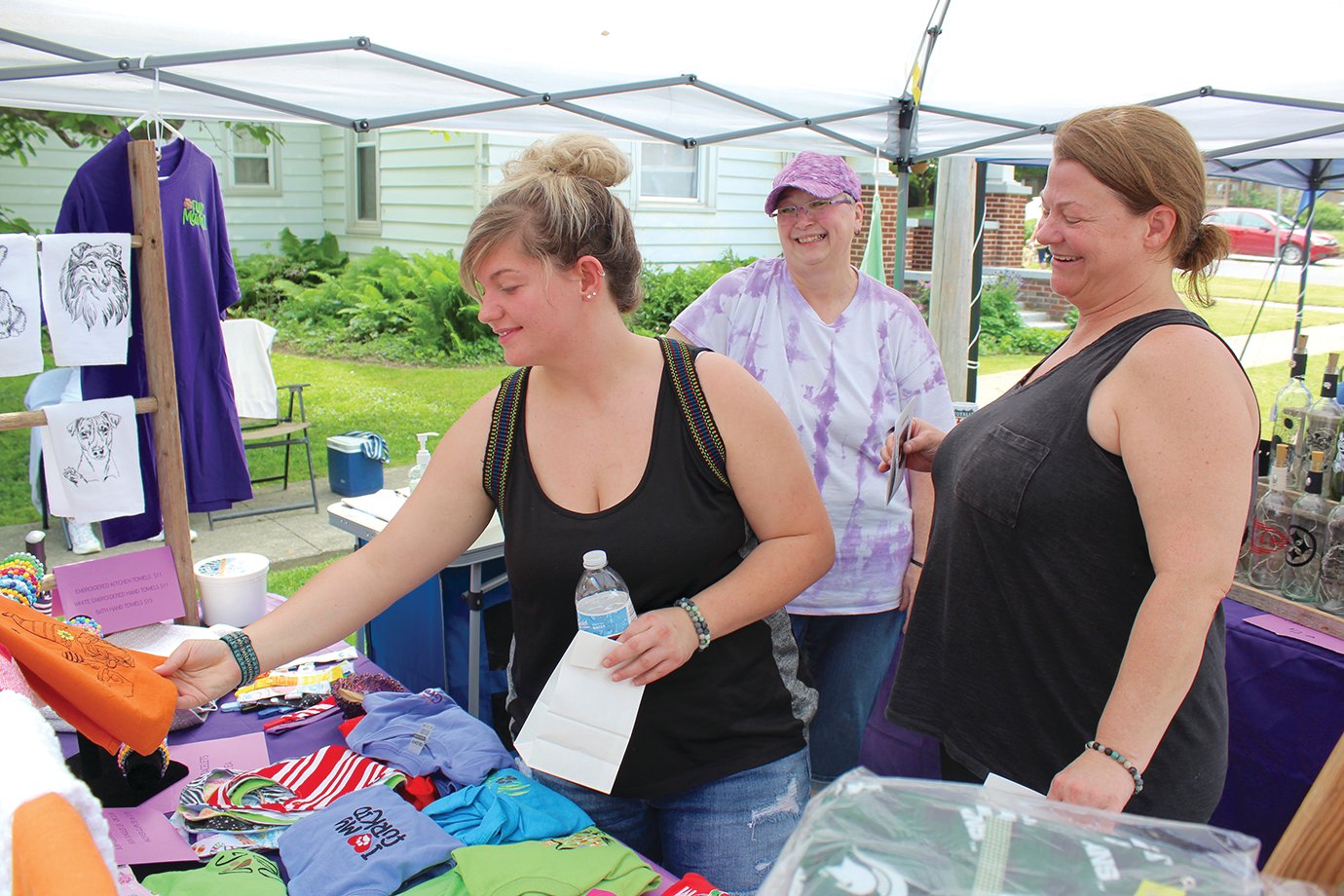 PurpleRoze owner and booth operator Ruby Rahm, center, assists Sheilah Price, left, and mother Eryn Price Saturday at the Waynetown Street Festival.